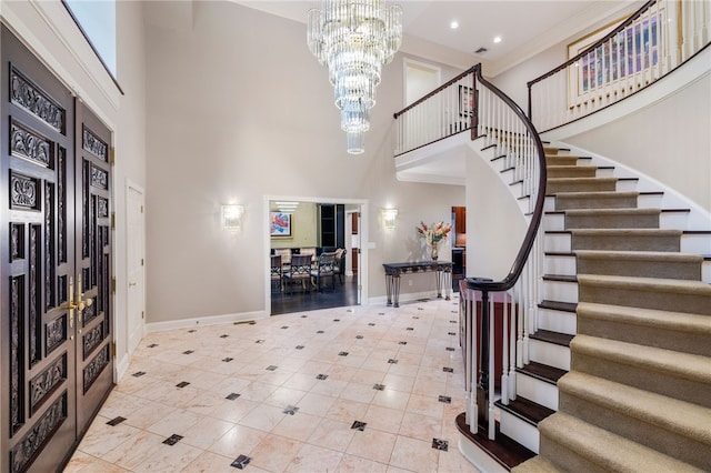 tiled entryway with ornamental molding, a high ceiling, and a chandelier