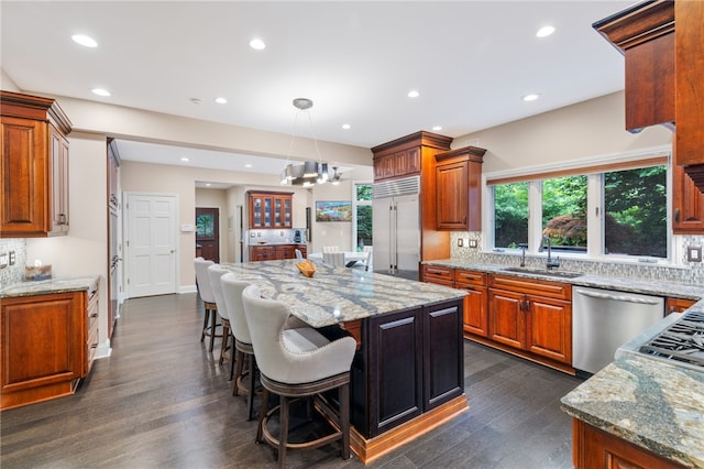 kitchen with sink, a center island, tasteful backsplash, pendant lighting, and appliances with stainless steel finishes