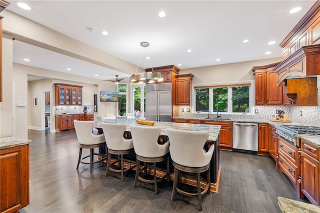 kitchen with sink, hanging light fixtures, a breakfast bar, a kitchen island, and appliances with stainless steel finishes