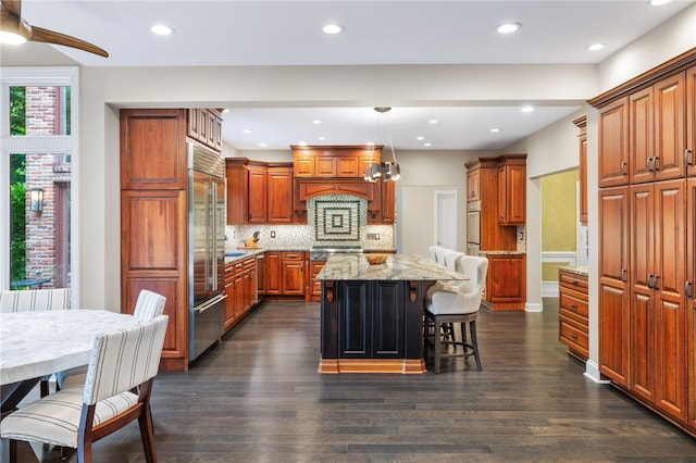 kitchen featuring a kitchen bar, backsplash, pendant lighting, a center island, and dark hardwood / wood-style floors