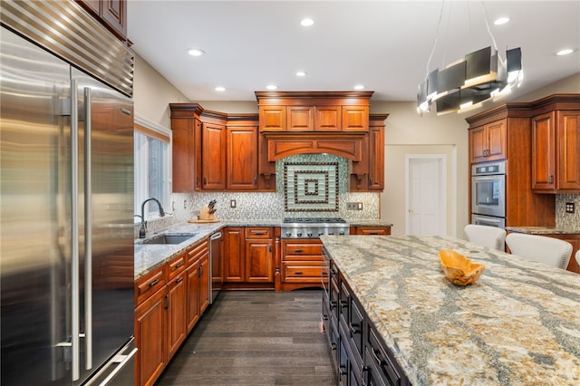 kitchen featuring stainless steel appliances, light stone counters, dark hardwood / wood-style floors, and sink