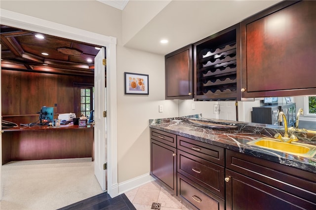 bar featuring dark stone countertops, sink, light tile patterned floors, and plenty of natural light