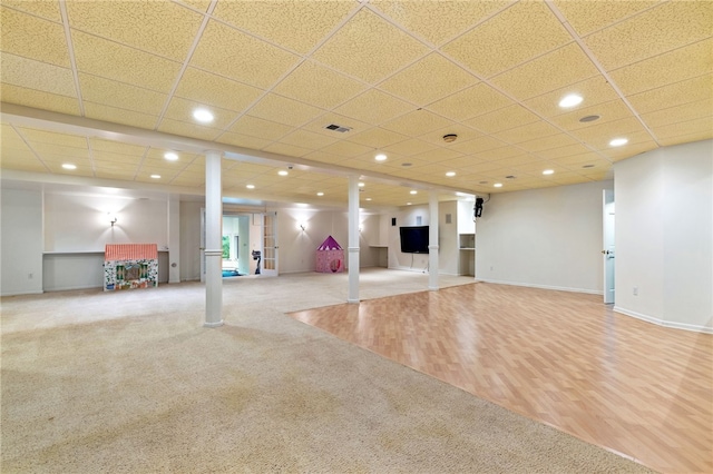 basement featuring french doors, carpet floors, and a drop ceiling