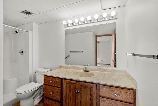 bathroom with vanity with extensive cabinet space, walk in shower, toilet, and a paneled ceiling