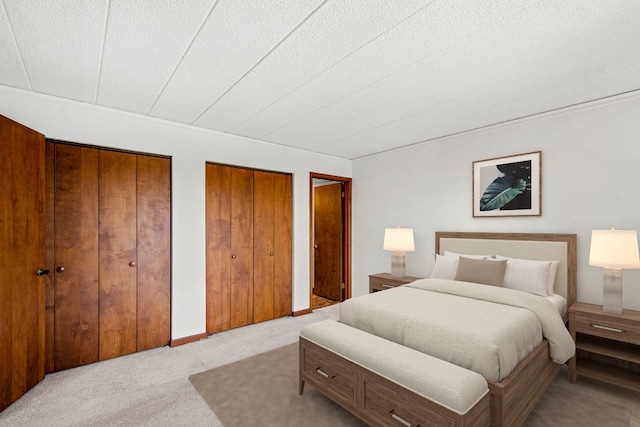 bedroom featuring multiple closets and light carpet