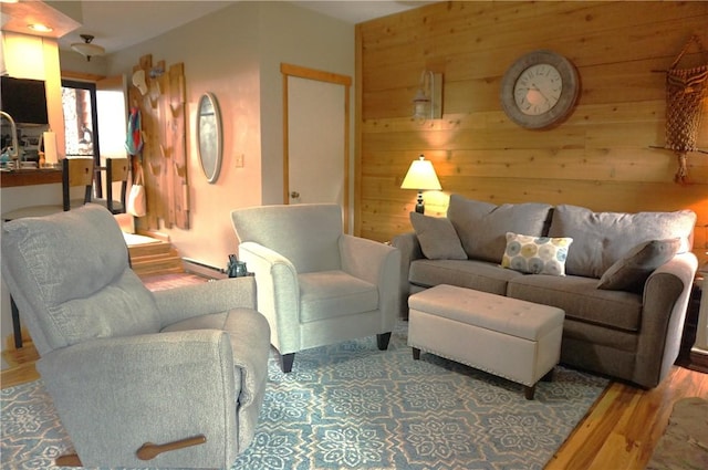 living room featuring a baseboard heating unit, wooden walls, and light hardwood / wood-style flooring