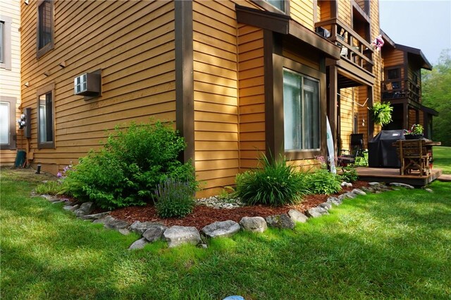 view of property exterior featuring a balcony, a yard, and a wall unit AC