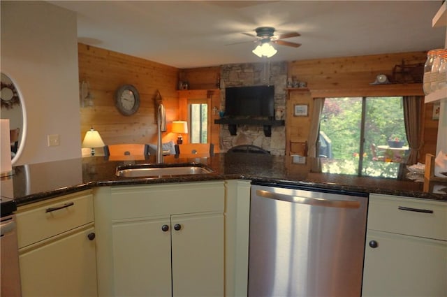 kitchen featuring dark stone counters, stainless steel dishwasher, wood walls, and kitchen peninsula