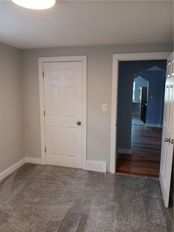 unfurnished bedroom with a closet and dark carpet