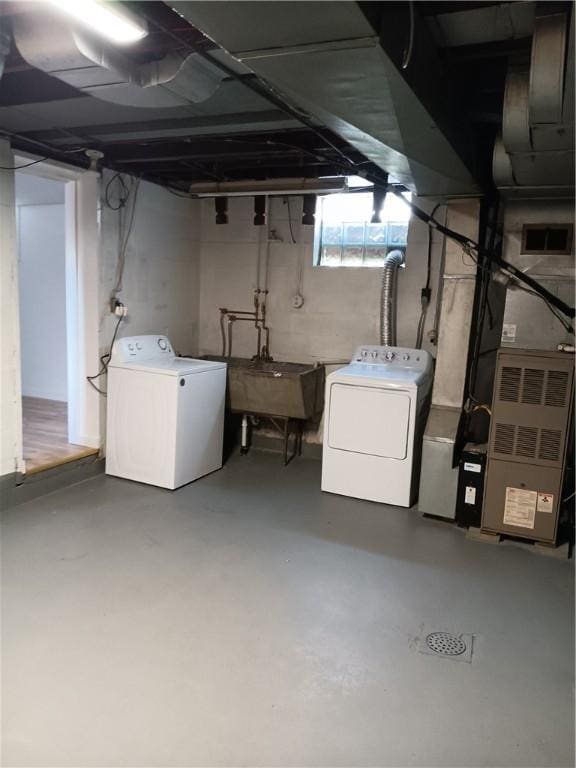 basement with heating unit, sink, and washing machine and clothes dryer