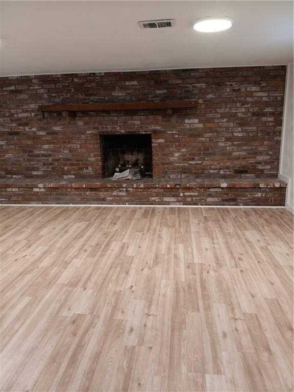 interior space with wood-type flooring and a brick fireplace