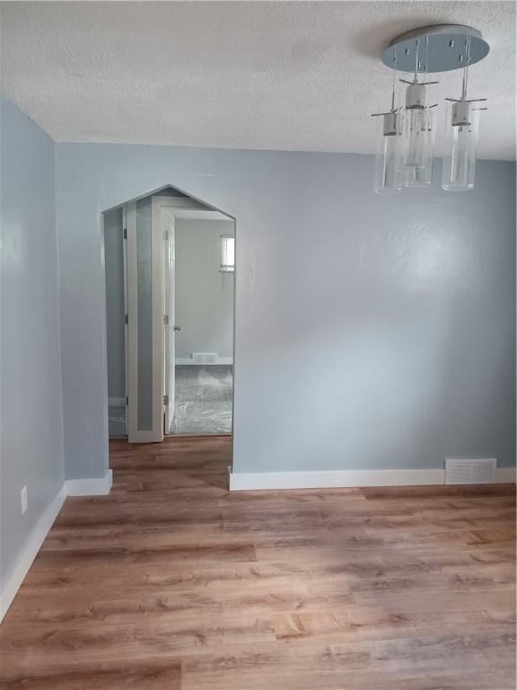 unfurnished room with hardwood / wood-style flooring and a textured ceiling