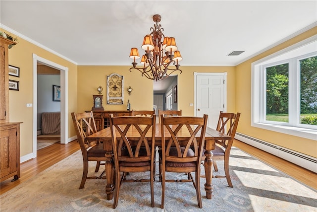 dining space with a chandelier, crown molding, baseboard heating, and light wood-type flooring