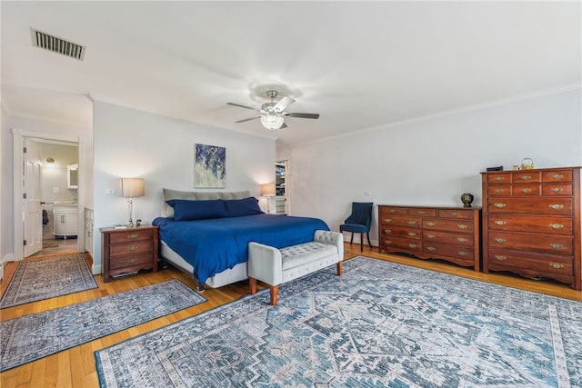 bedroom featuring crown molding, hardwood / wood-style flooring, ceiling fan, and ensuite bath