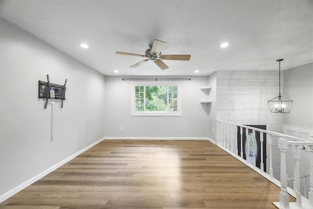 spare room with hardwood / wood-style floors and ceiling fan with notable chandelier