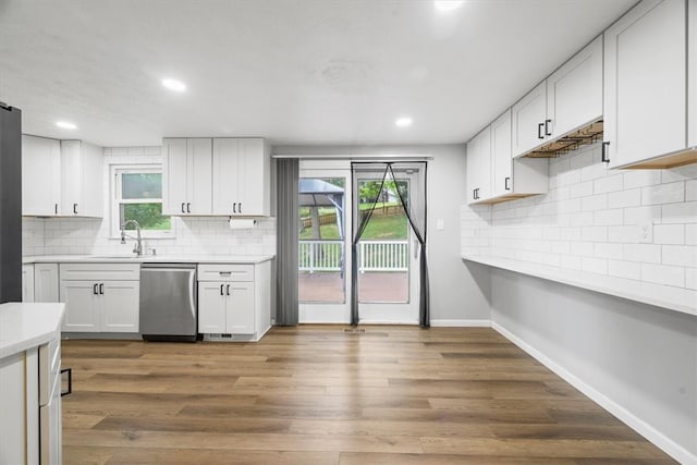 kitchen featuring dishwasher, hardwood / wood-style flooring, white cabinetry, and tasteful backsplash