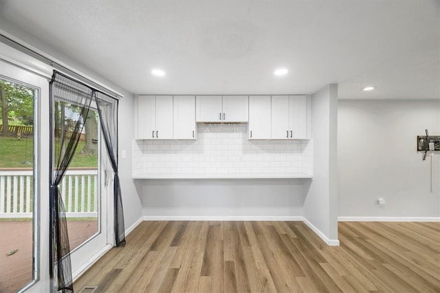 kitchen featuring backsplash, white cabinets, plenty of natural light, and light hardwood / wood-style floors