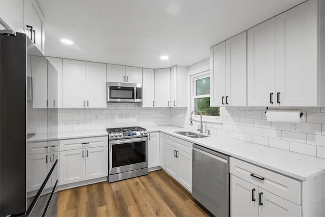 kitchen with stainless steel appliances, white cabinets, sink, and wood-type flooring