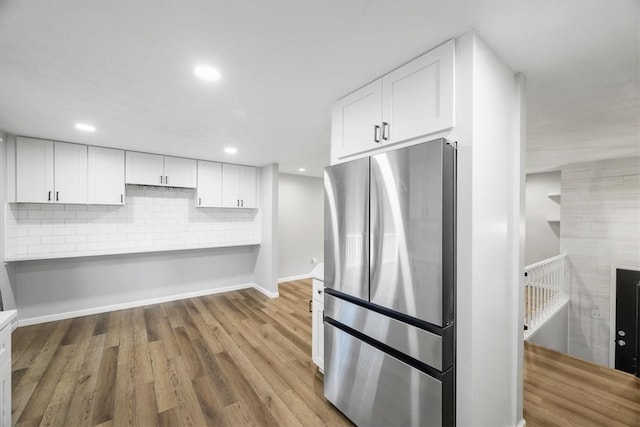 kitchen featuring wood-type flooring, white cabinetry, and stainless steel fridge