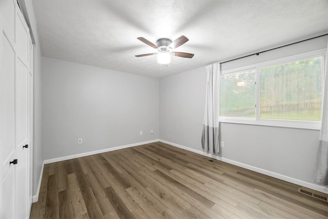 unfurnished bedroom featuring wood-type flooring, ceiling fan, and multiple windows