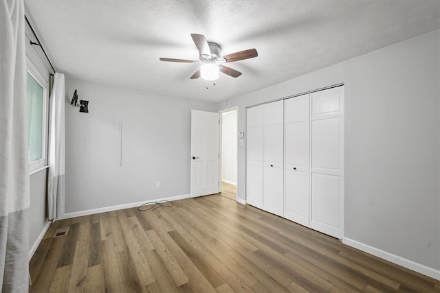 unfurnished bedroom featuring ceiling fan, a closet, a textured ceiling, and hardwood / wood-style flooring