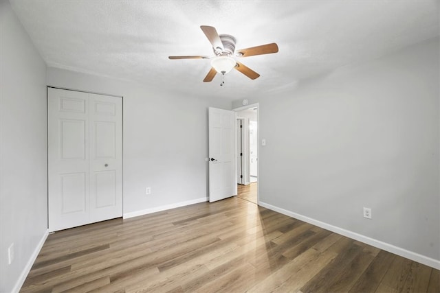 unfurnished bedroom with hardwood / wood-style flooring, a closet, and ceiling fan