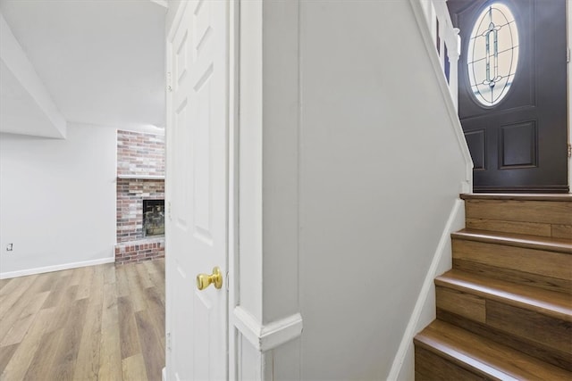 stairway with hardwood / wood-style flooring, brick wall, and a brick fireplace