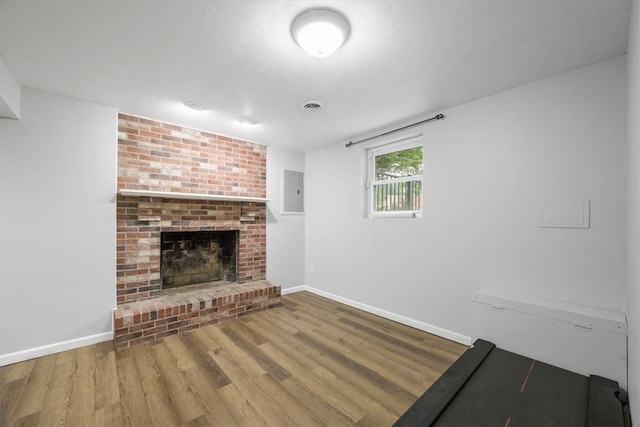 unfurnished living room with hardwood / wood-style flooring, brick wall, and a fireplace