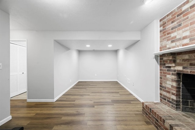 interior space featuring brick wall, wood-type flooring, a textured ceiling, and a fireplace