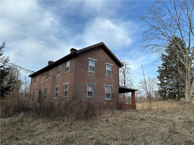 view of side of property featuring brick siding and a chimney