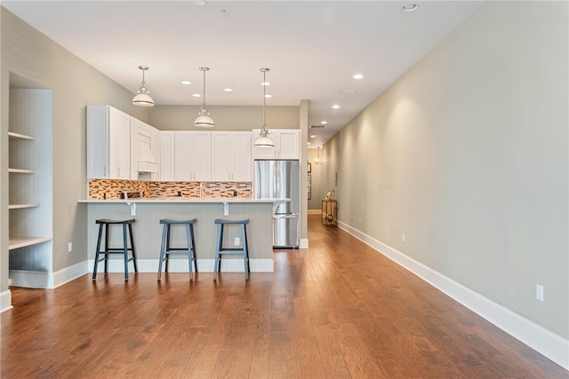301 5th Ave Unit 603, Downtown Pgh, PA 15222 - kitchen with freestanding refrigerator, a peninsula, light countertops, dark wood-type flooring, and white cabinetry
