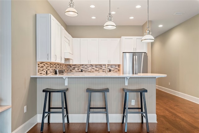 kitchen with decorative backsplash, dark hardwood / wood-style floors, stainless steel refrigerator, and white cabinets