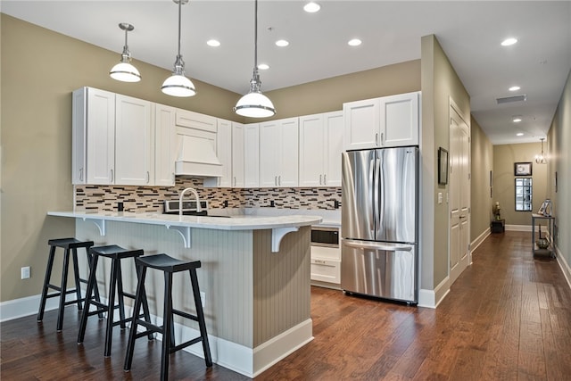 kitchen with white cabinetry, tasteful backsplash, custom range hood, stainless steel refrigerator, and dark wood-type flooring