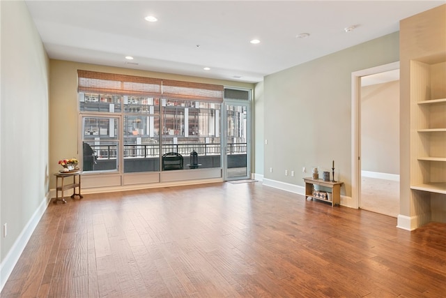 empty room featuring hardwood / wood-style flooring and built in shelves