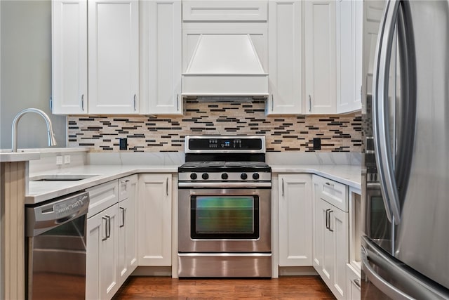 kitchen with white cabinetry, stainless steel appliances, hardwood / wood-style floors, sink, and custom range hood