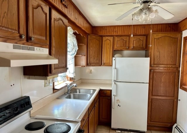 kitchen with white refrigerator, a baseboard radiator, ceiling fan, range, and sink