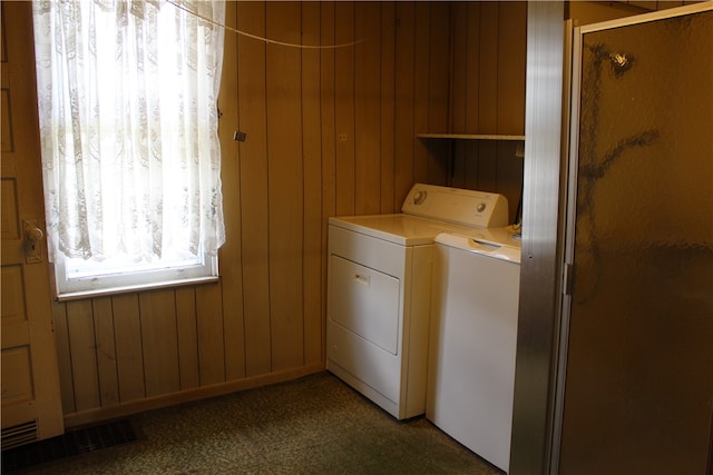 laundry area with washing machine and dryer, dark colored carpet, and wood walls