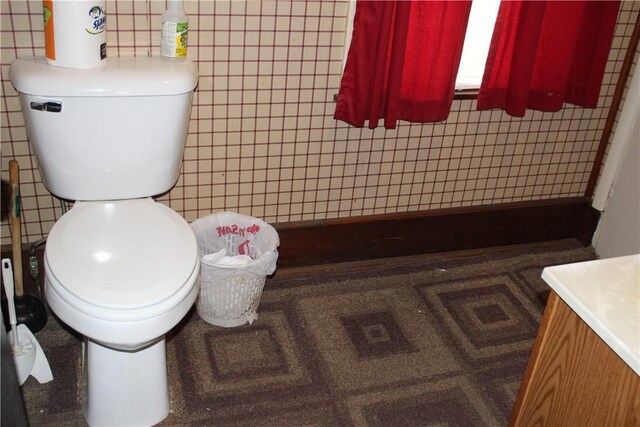 bathroom featuring vanity, toilet, and tile walls