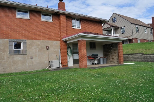 rear view of property with a yard, cooling unit, and a patio