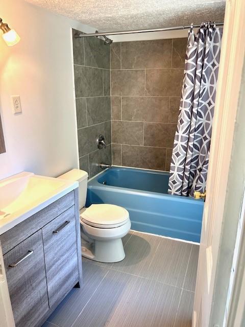 full bathroom with vanity, toilet, a textured ceiling, and shower / bath combo with shower curtain