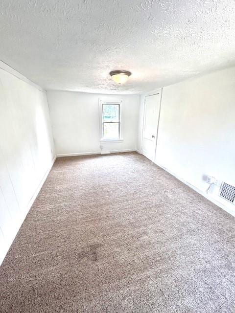 carpeted empty room featuring a textured ceiling