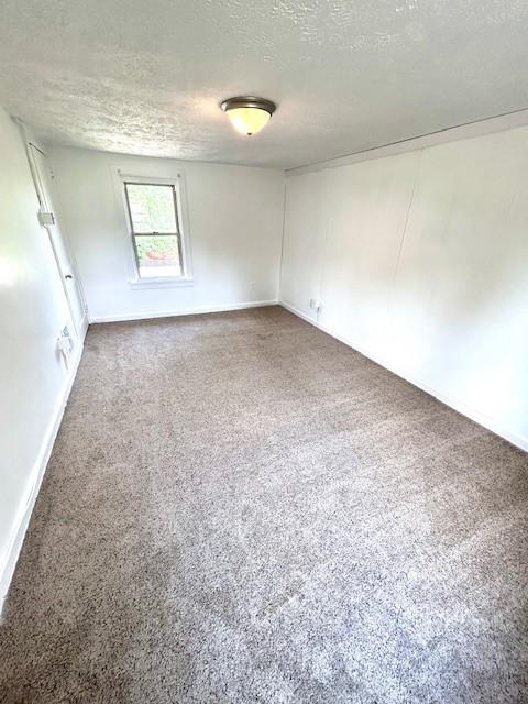 empty room with carpet and a textured ceiling