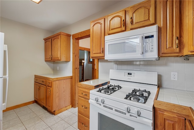 kitchen with tasteful backsplash, light tile floors, white appliances, and tile counters