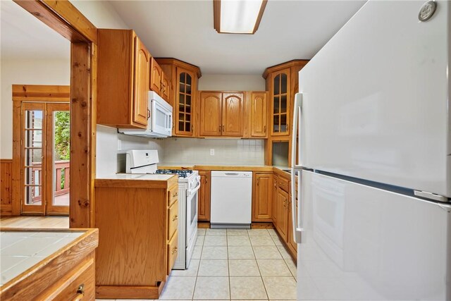 kitchen featuring tile counters, tasteful backsplash, white appliances, and light tile floors