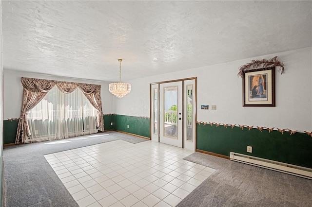 spare room featuring a baseboard heating unit, tile flooring, a healthy amount of sunlight, and a textured ceiling