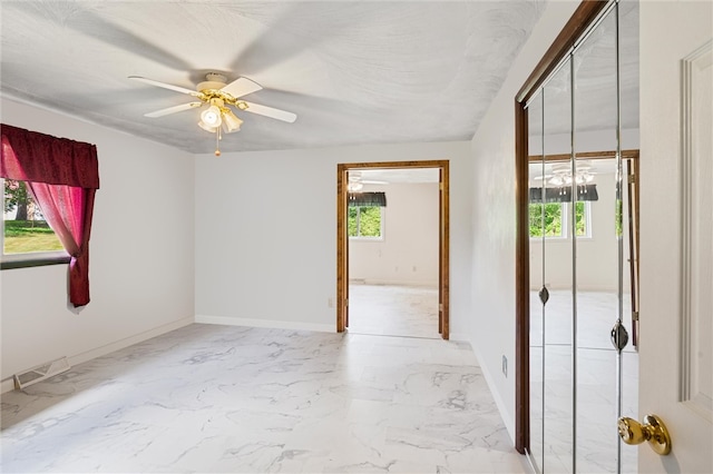 tiled empty room featuring ceiling fan and a wealth of natural light