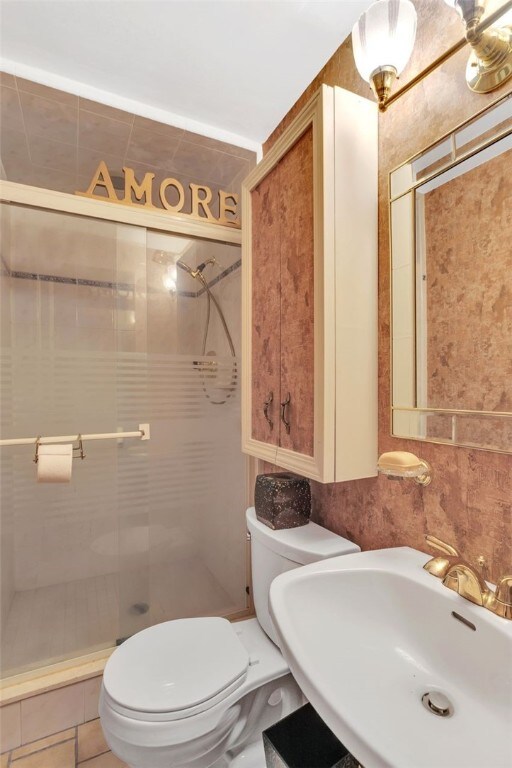 bathroom featuring tile walls, a shower with shower door, tile floors, sink, and toilet