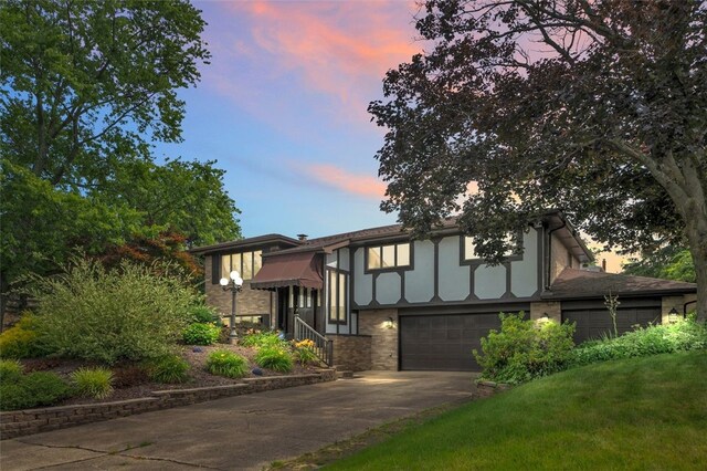 english style home with a garage and a yard