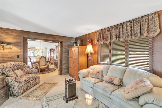 carpeted living room with a notable chandelier and brick wall