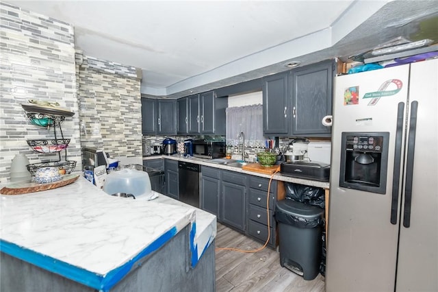 kitchen featuring light wood-type flooring, stainless steel appliances, backsplash, and sink